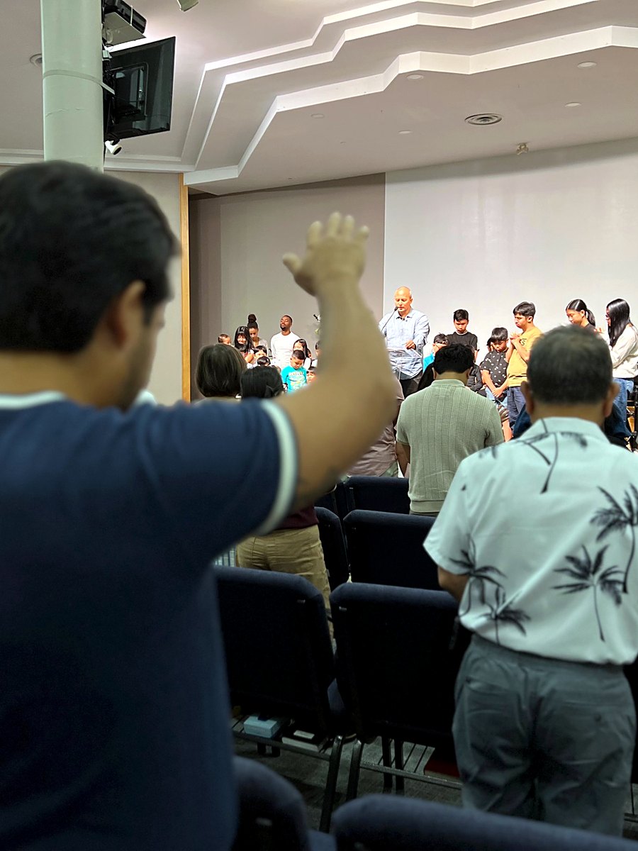 The congregation in prayer as the pastor prays over the children and youth on stage